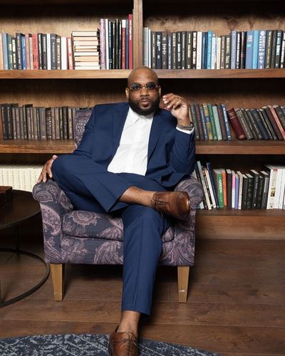 JaQuavis Coleman seated in front of a wall of bookshelves